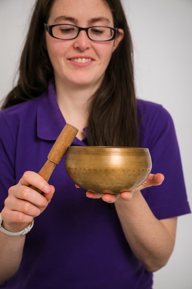 Solas Relaxation owner in a Relax Kids t shirt with a Tibetan singing bowl